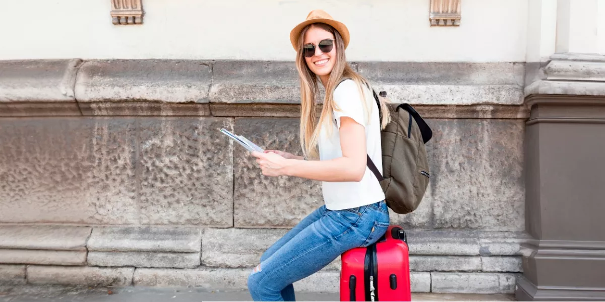 Joven-viajera-con-maleta-roja-y-mapa-en-mano